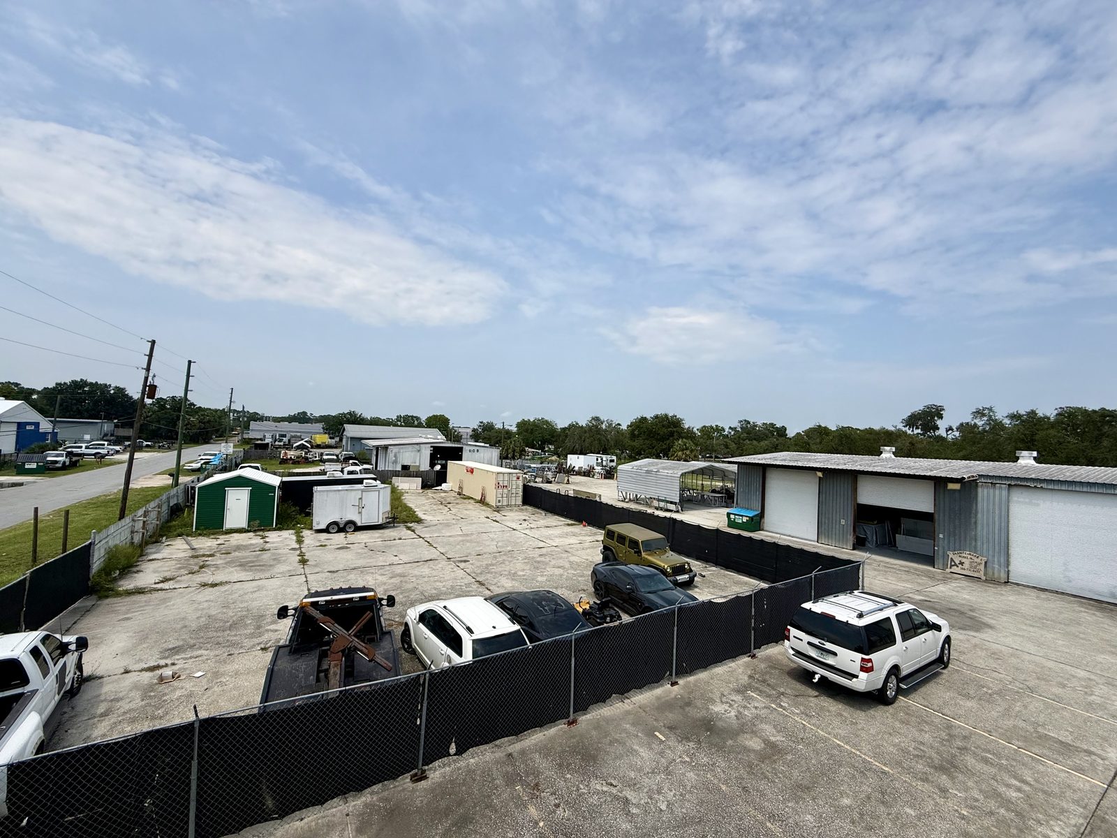 Elevated view across the property - fabrication buildings, fenced yard, and tenant parking